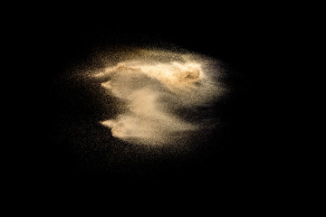 Golden sand explosion isolated on black background. Abstract sand cloud. Golden colored sand splash...