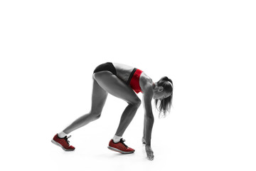 Fototapeta na wymiar Portrait of young sporty woman at starting block of race isolated over white studio background. The sprinter, jogger, exercise, workout, fitness, training, jogging concept. Profile