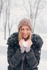 Attractive blonde woman holding snow outdoors.