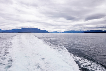 Wake Of Boat On Lake In Alaska Surrounded By Mountains And Forests