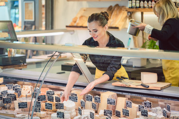 Verkäuferin sortiert Käse in Theke im Supermarkt ein