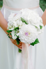 A bride in a beautiful dress is holding in hand a wedding bouquet of bright flowers. Florist and floral background. Valentine's Day, Wedding Day, romantic day, love story