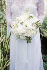 A bride in a beautiful dress is holding in hand a wedding bouquet of bright flowers. Florist and floral background. Valentine's Day, Wedding Day, romantic day, love story