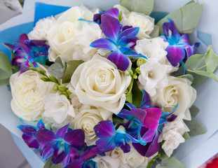 Bouquet of white roses and blue orchids.