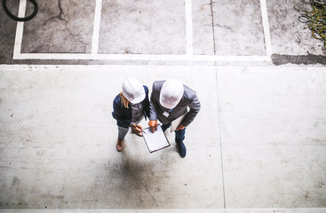 A top view of an industrial man and woman engineer with clipboard in a factory.