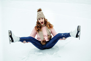 Beautiful girl in warm clothes sitting on ice rink after falling and laughing © matilda553