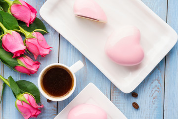 Fototapeta na wymiar Heart shaped mousse cakes, coffee and flowers.