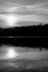 Beautiful lake and forest landscape during a colorful and dramatic sunset in monochrome