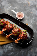 Szechuan Chicken which is a popular Indo-Chinese non vegetarian recipe. served in a plate with chilli sauce. selective focus