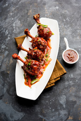 Szechuan Chicken which is a popular Indo-Chinese non vegetarian recipe. served in a plate with chilli sauce. selective focus