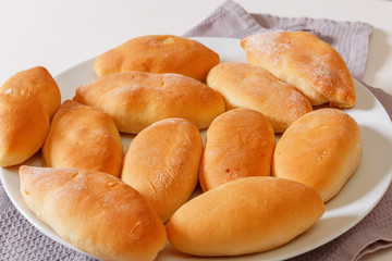 Close-up, homemade cooking. Little pies are lying on a white plate