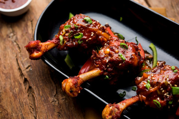 Szechuan Chicken which is a popular Indo-Chinese non vegetarian recipe. served in a plate with chilli sauce. selective focus