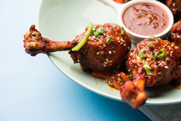 Szechuan Chicken which is a popular Indo-Chinese non vegetarian recipe. served in a plate with chilli sauce. selective focus