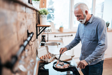 Handsome senior man cooking at home.