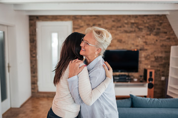 It's lovely to see you. Adult mother and daughter hugging at home.