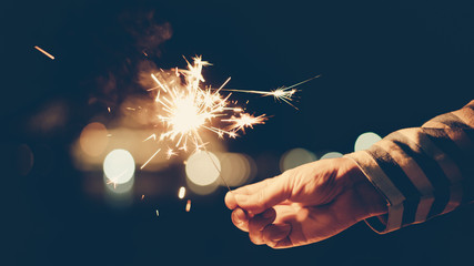 woman with striped shirt holding sparklers in the dark