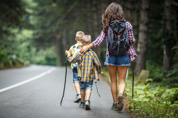 Mother and her little sons hiking by the rural country road.Outdoor spring leisure concept.