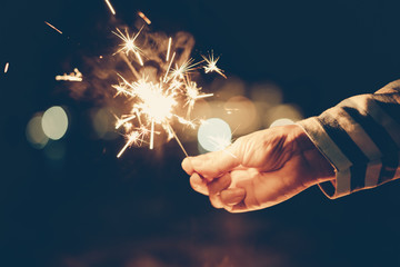 woman with striped shirt holding sparklers in the dark