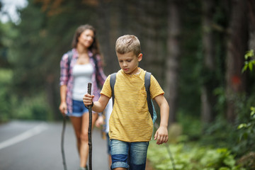 Mother and her little sons hiking by the rural country road.Outdoor spring leisure concept.