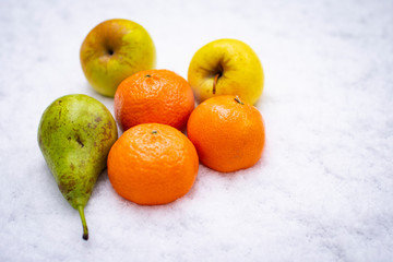 Fruits on the snow, mandarines, apples, pear