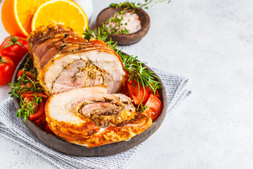 Classic Italian baked porchetta with oranges, copy space. Baked pork on white background. Italian cuisine concept.