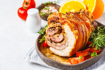 Classic Italian baked porchetta with oranges, copy space. Baked pork on white background. Italian cuisine concept.