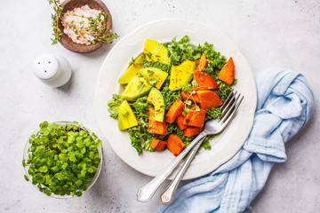 Healthy green kale salad with avocado and baked sweet potatoes. Plant based diet concept, detox food.