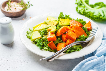 Healthy green kale salad with avocado and baked sweet potatoes. Plant based diet concept, detox food.