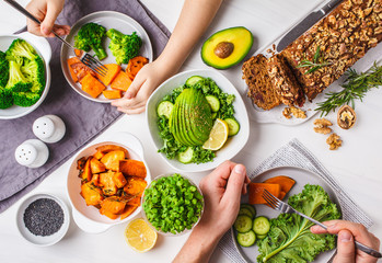Healthy vegan food lunch, top view. Vegetarian dinner table, people eat healthy food. Salad, sweet potato, vegan cake, vegetables on white background.