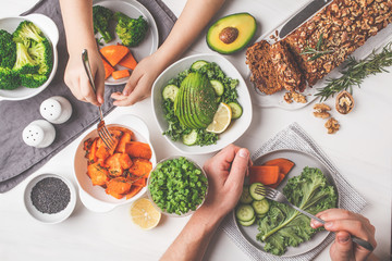Healthy vegan food lunch, top view. Vegetarian dinner table, people eat healthy food. Salad, sweet...