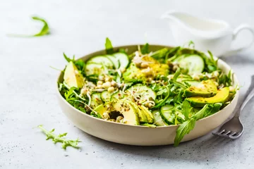 Foto auf Acrylglas Healthy green salad with avocado, cucumber and arugula in white dish. © vaaseenaa