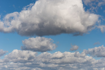 Beautiful white and grey fluffy clouds soar over a deep blue background. Cloudscape with autumn...
