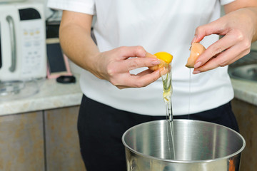 A woman is cooking in her kitchen, about to bake a cake. woman breaks eggs, separates proteins from yolks