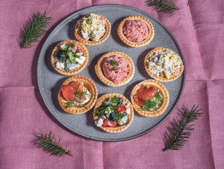 Tartlets with various salads on a large ceramic dish.
