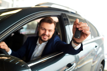 Male driver smiling holds the keys to the car