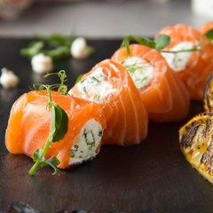 Salmon rolls stuffed with cream cheese and herbs, beautiful snack, elegant food for menu