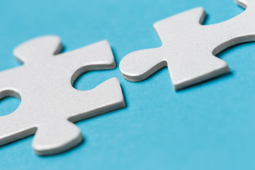 Close-up of two blank white puzzle pieces on blue background