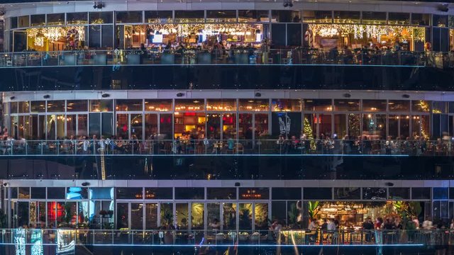 Circular building with different restaurants at each floor in the heart of Dubai Marina district night timelapse.