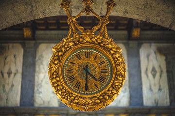 Fototapeta na wymiar antique hanging clock with roman numerals in the hall with marble walls