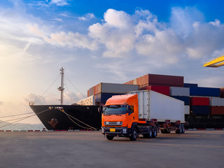 The container vessel  during discharging at an industrial port and move containers to container yard by trucks.