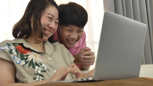 4K Family lifestyle is playing computer games. Asian Mother and son watching on laptop computer with smile face.