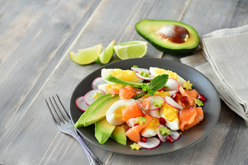 Salad with organic avocado and with salmon, eggs and radish. Decorated with mint leaf and pomegranate. Healthy lunch, vegetarian food, diet dish. food for weight loss. Selective focus and copy space