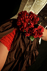 woman showing thigh while wearing burlesque/ steampunk outfit, holding bouquet of roses on hip.