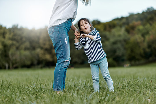 Image of cute happy little girl playing with her beautiful mother outdoors in the park. Happy family time together. Positive emotion. Good relationship between mom and daughter. Mother's day concept