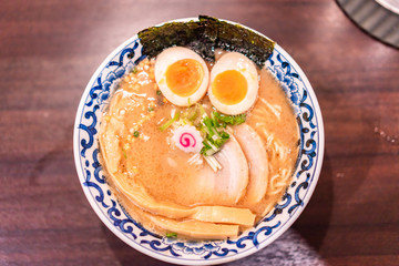 Japanese ramen soup with chicken, egg, chives and sprout on dark wooden background