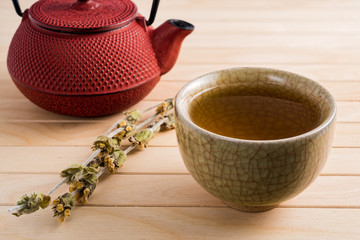 Cup of tea and japanese traditional style red teapot with dry tea on wooden table