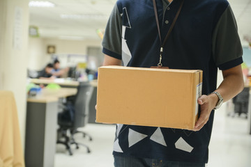Delivery man holding cardboard boxes in office
