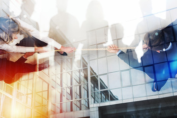 Rival business man and woman compete for the command by pulling the rope. Double exposure effect