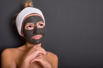 Beautiful woman taking care of her beauty with a clay mask on her face