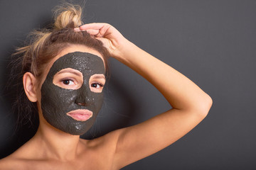 Perfect black mask made of clay on the face of a beautiful woman